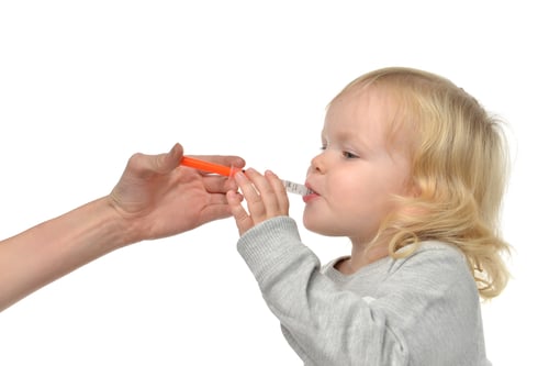 child takes liquid medicine with syringe